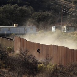 Man climbing the border wall (photo by Marc Silver)